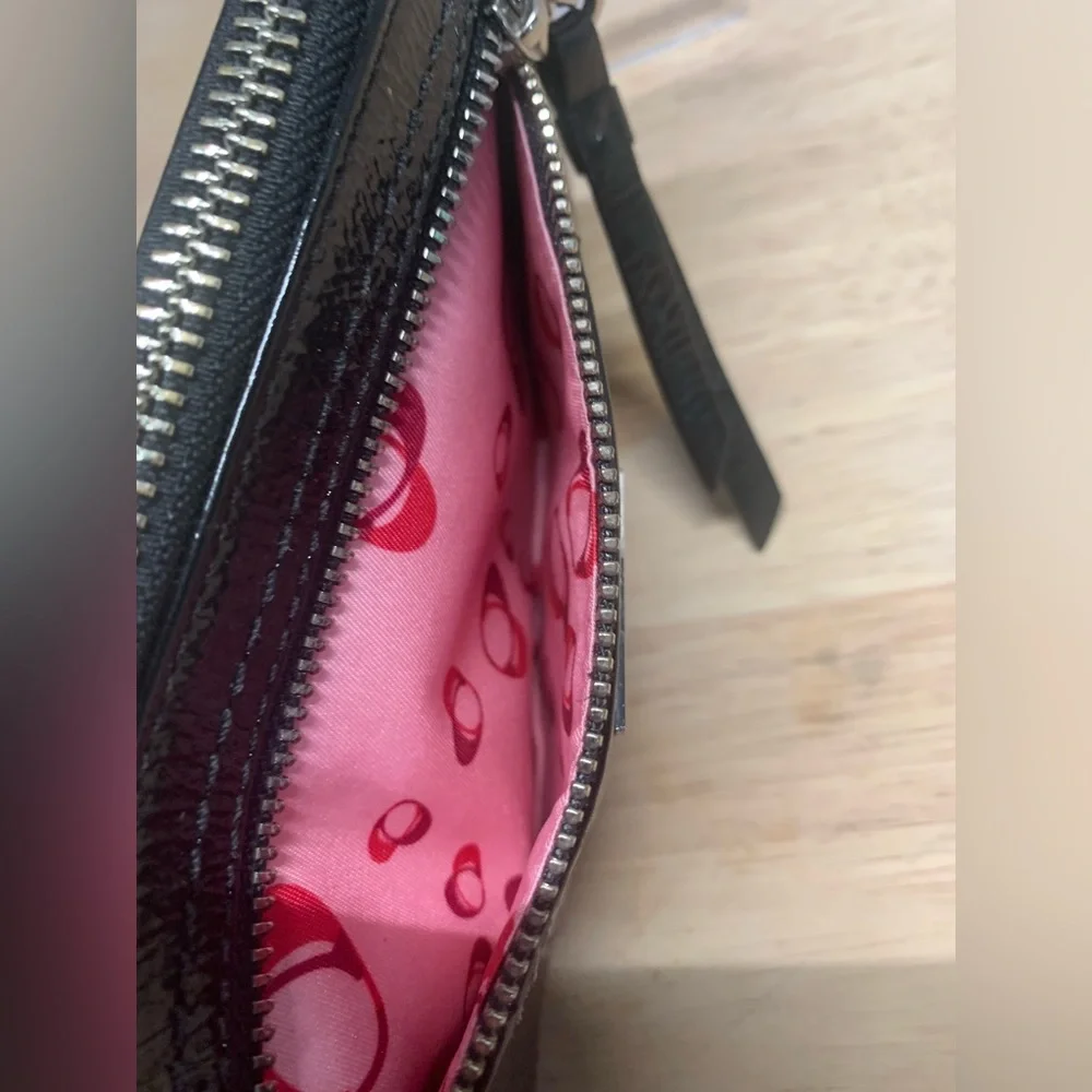 Coach Poppy Black patent leather wristlet with pink poppy interior.